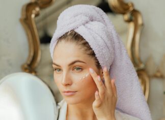 Woman Looking in the Mirror and Applying a Face Cream